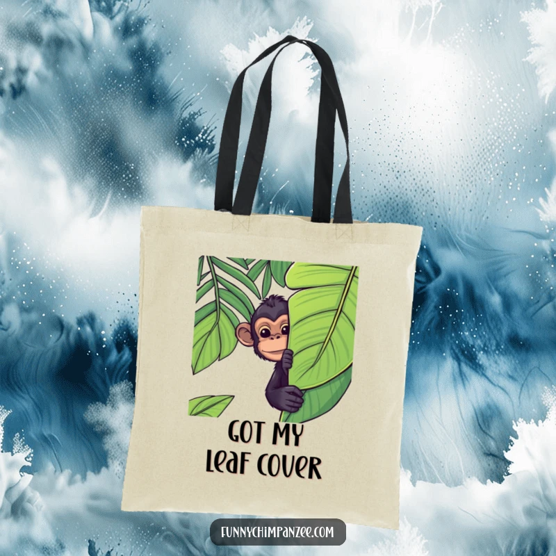 Funny Kawaii chimpanzee peeking from behind a large, tropical jungle leaf on a tote bag, its expression full of playful curiosity.